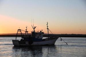 Fishing boat in the sea at sunset photo