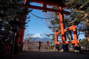 Travel Japan on winter, Woman raised hands with a giant torii gate or Red pole and fuji mountains. photo