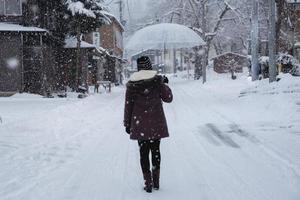 Travel in Japan, Girl with umbrella walking on the path in the village on Winter. photo