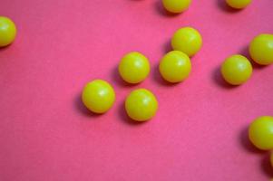 bright yellow vitamins of round volumetric form on a pink background. pills to strengthen human immunity in the midst of coronavirus and for health problems. flatlet from pills, background for drugs photo