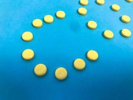 bright yellow volumetric tablets stylized in the form of letters to form words. pills against viral infections for immunity and strengthening human health on a blue background photo