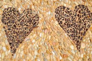 The texture of the stone wall, the road from small round and oval stones with abstracted lines of patterns of two hearts sandy seams of natural old yellow black brown. The background photo