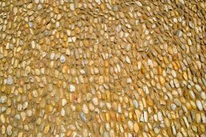 Texture of a stone wall, roads from small round and oval stones with sand with seams of natural old yellow black brown. The background photo