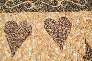 The texture of the stone wall, the road from small round and oval stones with abstracted lines of patterns of two hearts sandy seams of natural old yellow black brown. The background photo