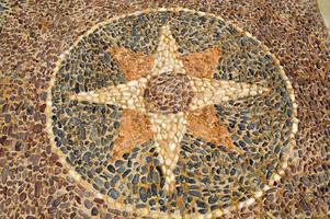 The texture of the stone wall, the road from small round and oval stones with abstracted lines of star patterns sandy seams of the natural old yellow black brown. The background photo