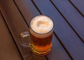 taza de cerveza con espuma densa blanca sobre un fondo de madera. foto