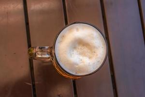 Mug of beer with white dense foam on a wooden background. photo