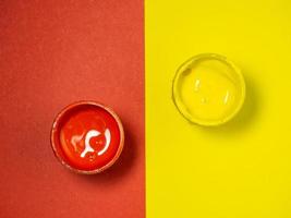 Jars with yellow and red paint on a yellow and red background. Bank of gouache. Bright background.  Artist's workshop. photo