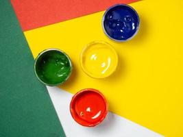 Jars with yellow, green and red paint on a color pepper. Banks of gouache.  Traffic lights. Creative background. Artist's workshop. photo