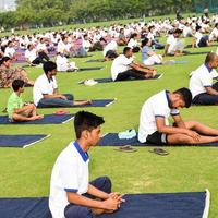 New Delhi, India, June 21 2022 - Group Yoga exercise session for people at Yamuna Sports Complex in Delhi on International Yoga Day, Big group of adults attending yoga class in cricket stadium photo