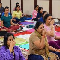 New Delhi, India, June 19 2022 -Group Yoga exercise session for people of different age groups in Balaji Temple, Vivek Vihar, International Yoga Day, Big group of adults attending yoga class in temple photo