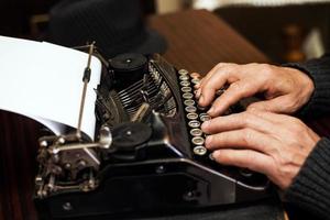 hombre que usa el primer plano de la máquina de escribir foto