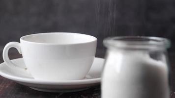 Adding a teaspoon of sugar to coffee or tea in ceramic mug video