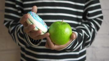 A teen in striped shirt chooses between a donut and green apple video