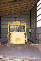 Large wheeled tractor with a dozer blade for clearing roads from snow. Yellow wheel loader in the garage. photo