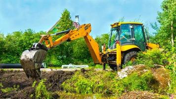 Excavator with bucket in the field among a grass photo