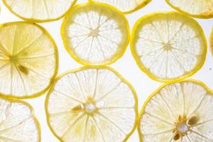 jugosas rodajas de limón con burbujas bajo el agua aisladas en fondo blanco. fondo de textura de patrón de rodajas de limón amarillo. foto