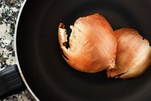 Onion skin in a frying pan on black and white marble background. Top view. Horizontal image. photo