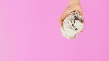 Crumpled paper. It is mauled in a woman's hand on pink backgrou photo