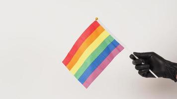 Hands are holding a movie slate or clapper board and a rainbow flag. Hands are wearing black latex gloves photo