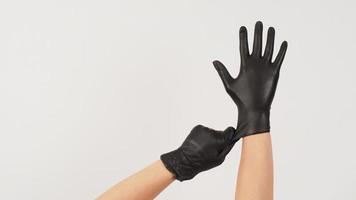 Hands is pulling black latex gloves on white background. photo