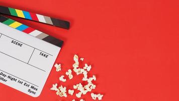 Clapper board or movie slate and popcorn on a red background. photo