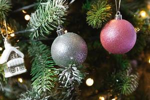 clásico árbol de año nuevo decorado con adornos de plata rosa juguete y bola y luces de guirnalda desenfocadas. diseño de vacaciones clásico moderno. Nochebuena en casa. foto