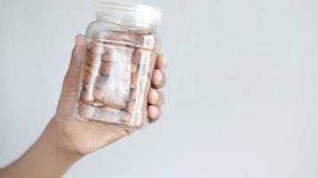 Adult holds a capped jar of whole almonds before a blank white background video