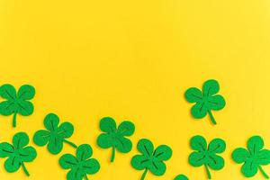 St Patricks Day background. Simply minimal design with green shamrock. Clover leaves isolated on yellow background. Symbol of Ireland. Lucky fortune wish concept. Flat lay top view layout copy space. photo