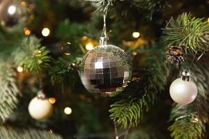 Classic Christmas New Year decorated New year tree with silver ornament decorations toy and ball and defocused garland lights. Modern classical holiday design. Christmas eve at home. photo