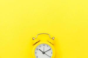 Ringing twin bell vintage classic alarm clock Isolated on yellow colourful trendy modern background. Rest hours time of life good morning night wake up awake concept. Flat lay top view copy space. photo