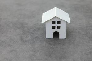 Simply design with miniature white toy model house on concrete stone grey background. Mortgage property insurance dream home concept. Copy space. photo