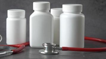 Pill bottles and a stethoscope on grey background video