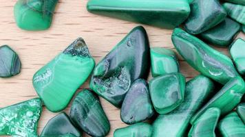 Malachite heap up jewel stones texture on light varnished wood background. Moving right seamless loop backdrop. video