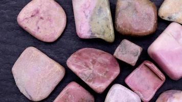 Rhodochrosite heap up jewel stones texture on black stone background. Moving right seamless loop backdrop. video