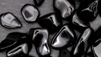 obsidianhaufen juwelensteine textur auf schwarzem steinhintergrund. sich nach rechts bewegender nahtloser Schleifenhintergrund. video
