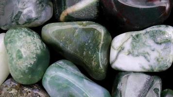 Moss agate heap jewel stones texture on white light background. Moving right seamless loop backdrop. video