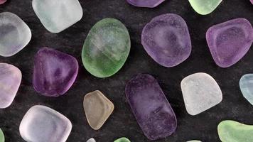 Fluorite rare jewel stones texture on black stone background. Moving right seamless loop backdrop. video