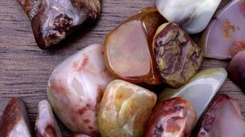 Yanyuan agate heap up jewel stones texture on brown varnished wood background. Moving right seamless loop backdrop. video