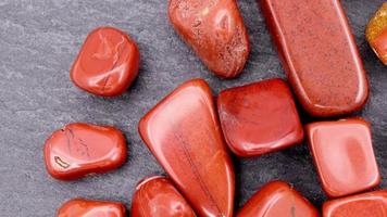 Red jasper heap up jewel stones texture on brown varnished wood background. Moving right seamless loop backdrop. video