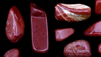 Red jasper rare jewel stones texture on black background. Moving right seamless loop backdrop. video