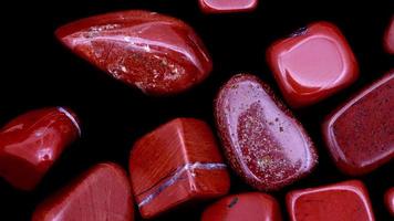 Red jasper heap up jewel stones texture on black background. Moving right seamless loop backdrop. video