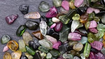 Tourmaline heap up jewel stones texture on black stone background. Moving right seamless loop backdrop. video