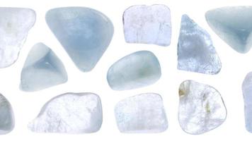 Aquamarine jewel stones set texture on light white isolated background. Macro closeup. Moving right seamless loop backdrop. video