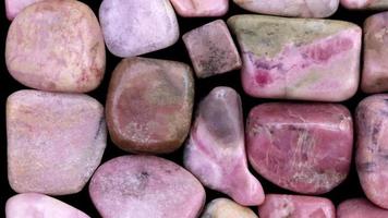 Rhodochrosite heap jewel stones filled texture on black background. Moving right seamless loop backdrop. video