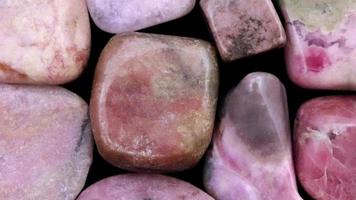 Rhodochrosite heap jewel stones filled texture on black background. Moving right seamless loop backdrop. video