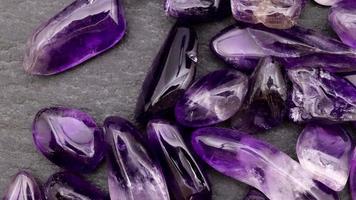 Amethyst heap up jewel stones texture on black stone background. Moving right seamless loop backdrop. video