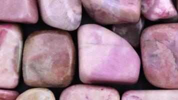 Rhodochrosite heap jewel stones filled texture on black background. Moving right seamless loop backdrop. video