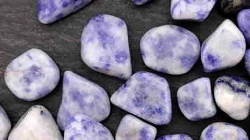 Sodalite heap up jewel stones texture on black stone background. Moving right seamless loop backdrop. video
