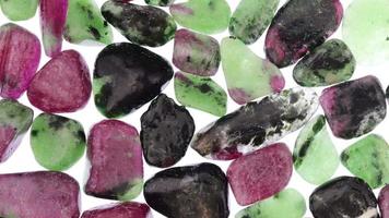 Ruby zoisite jewel stones heap texture on light white isolated background. Moving right seamless loop backdrop. video